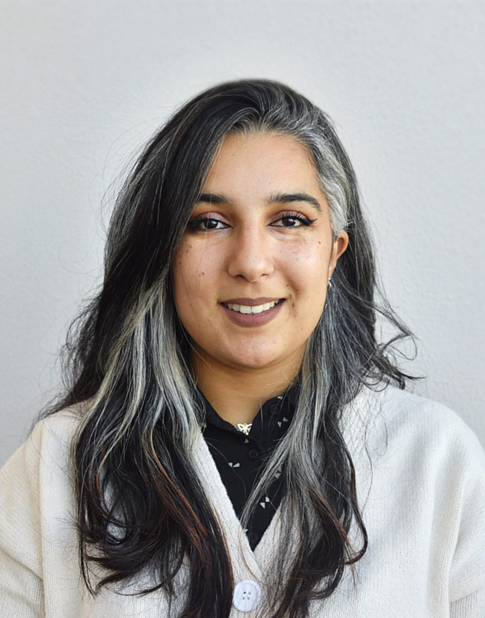 The picture shows a young woman with long, two-toned hair: she has dark hair with gray or white strands framing her face.